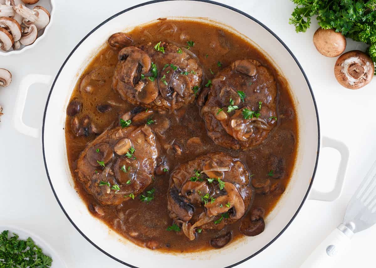 Salisbury steak cooking in a skillet.