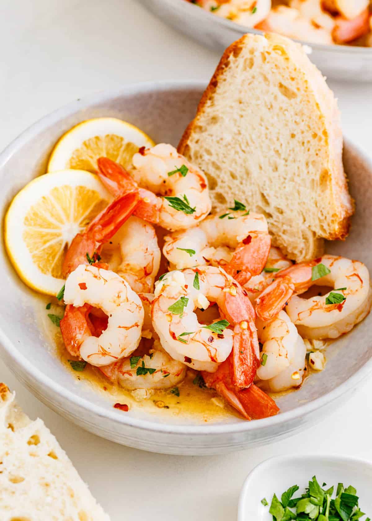 Shrimp scampi in a white bowl with bread.