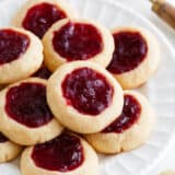 Thumbprint cookies with raspberry jam on a white plate.