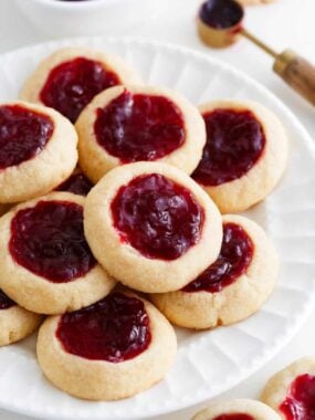 Thumbprint cookies with raspberry jam on a white plate.