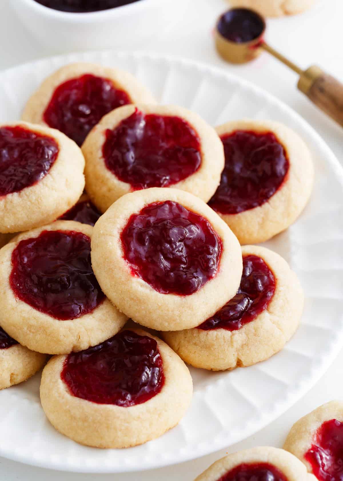 Thumbprint cookies with raspberry jam on a white plate.