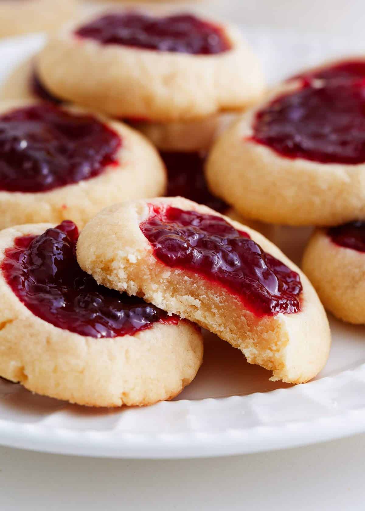 Thumbprint cookies with a bite taken on a white plate.