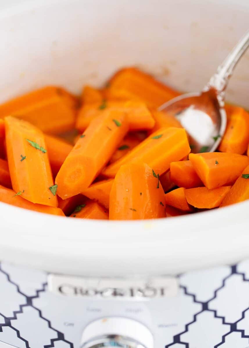 Brown sugar glazed carrots in a white crockpot.