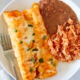 Cheese enchiladas with rice and beans on a plate.