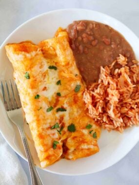 Cheese enchiladas with rice and beans on a plate.