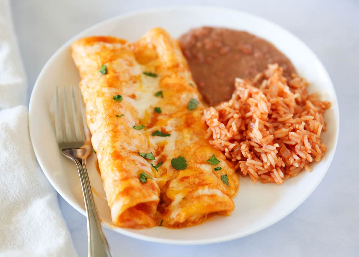 Cheese enchiladas with mexican rice and beans on a plate.