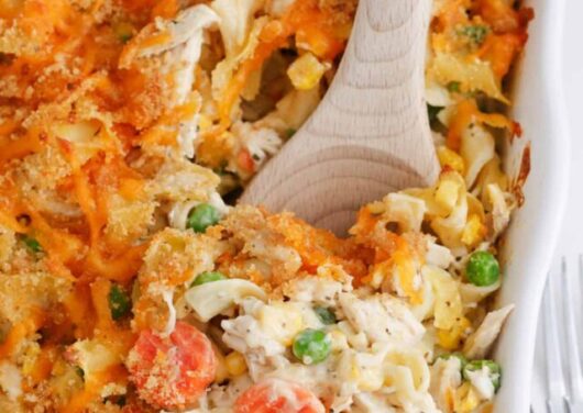 Spoonful of chicken noodle casserole in a white baking dish.