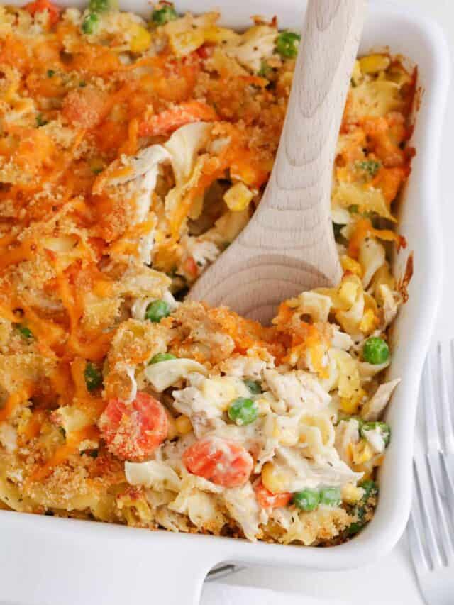 Spoonful of chicken noodle casserole in a white baking dish.