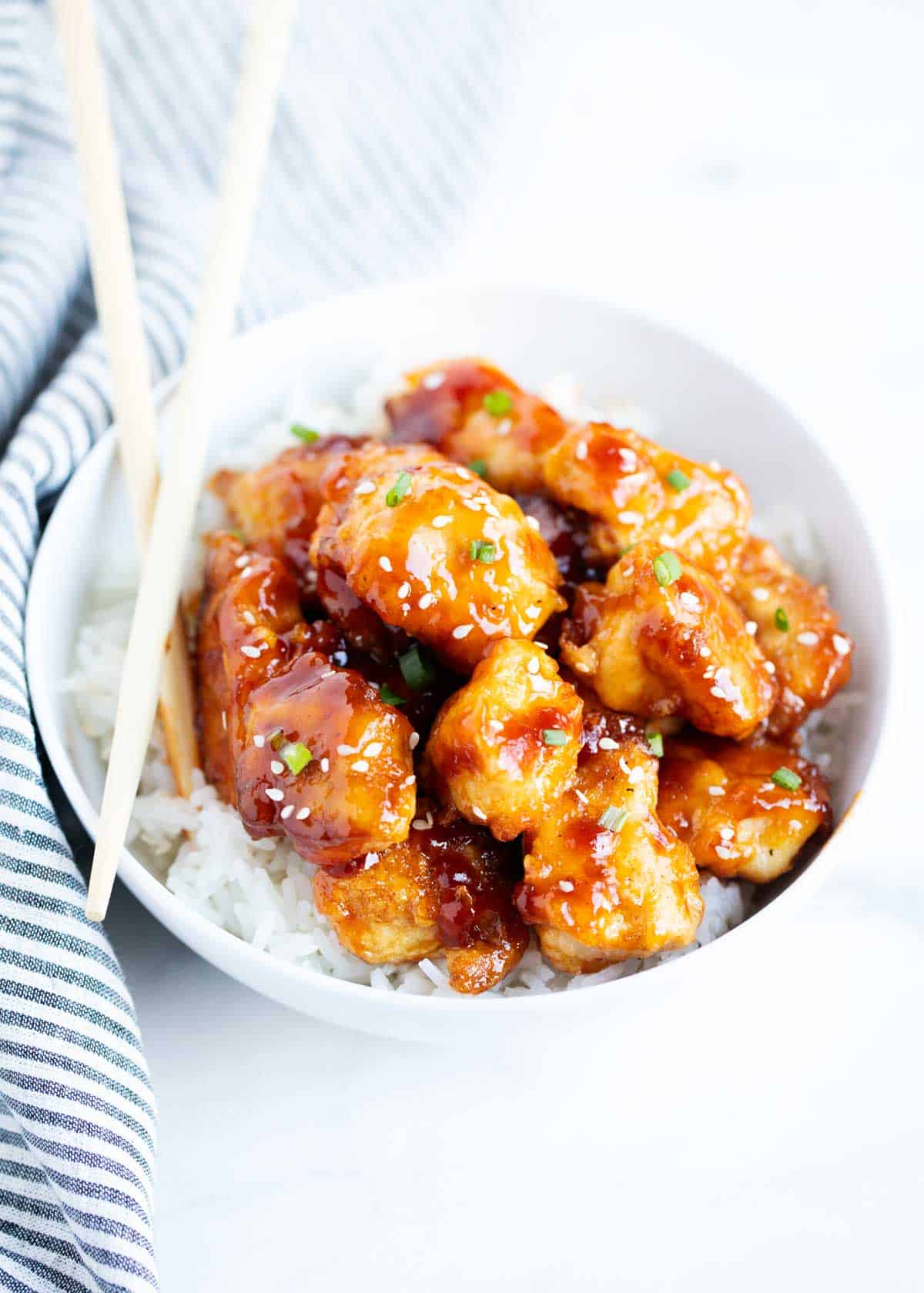 A white bowl with General Tso's chicken. 