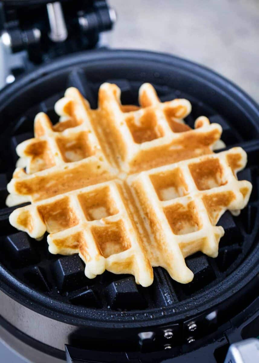 A Belgian waffle in a waffle iron. 