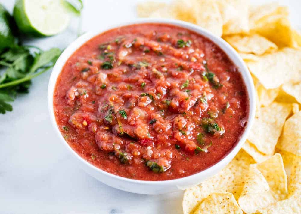 The absolute BEST restaurant style salsa that's made in the blender in less than 10 minutes! Easy, authentic and full of Mexican flavor. Salsa in a white bowl.
