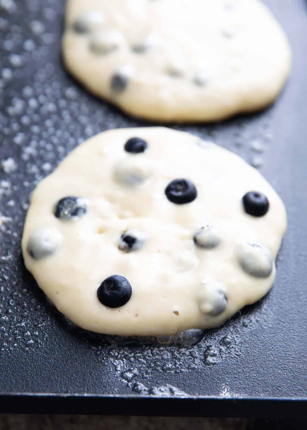 Blueberry pancakes on a griddle. 