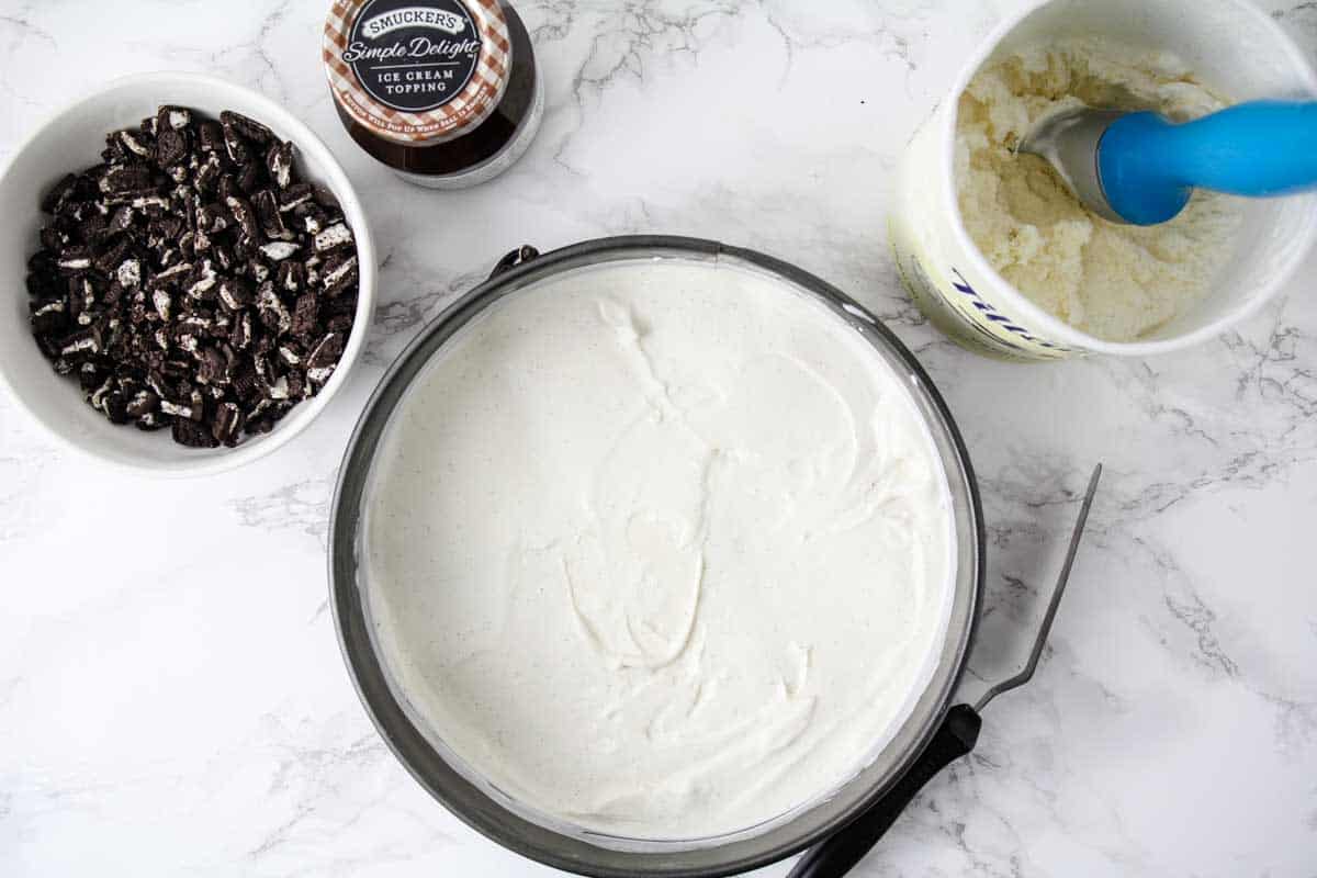 Ice cream, hot fudge, cake and crushed Oreos on the counter.