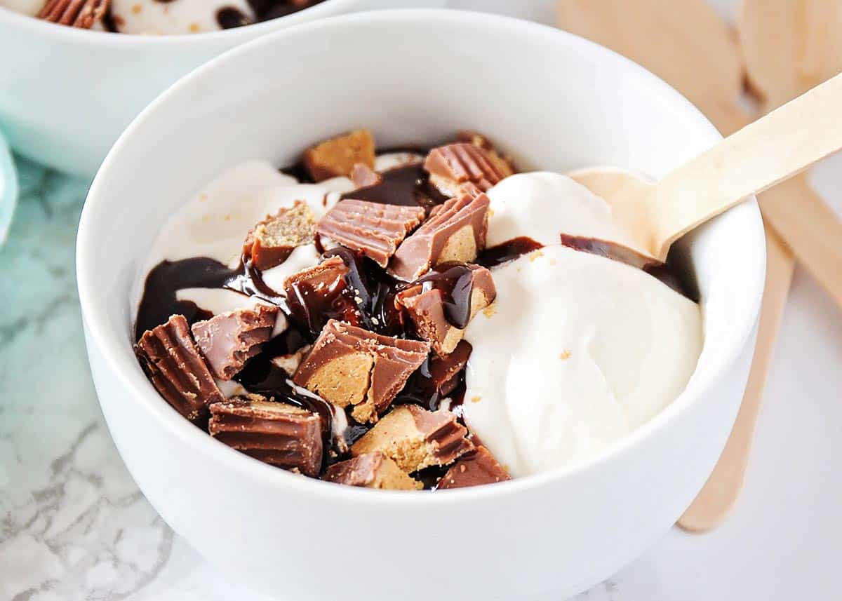 Reese's ice cream in a white bowl with a spoon in it. 