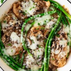 Copycat Cheesecake Factory chicken Madeira recipe with mushrooms, asparagus, and melted cheese in a savory wine sauce.