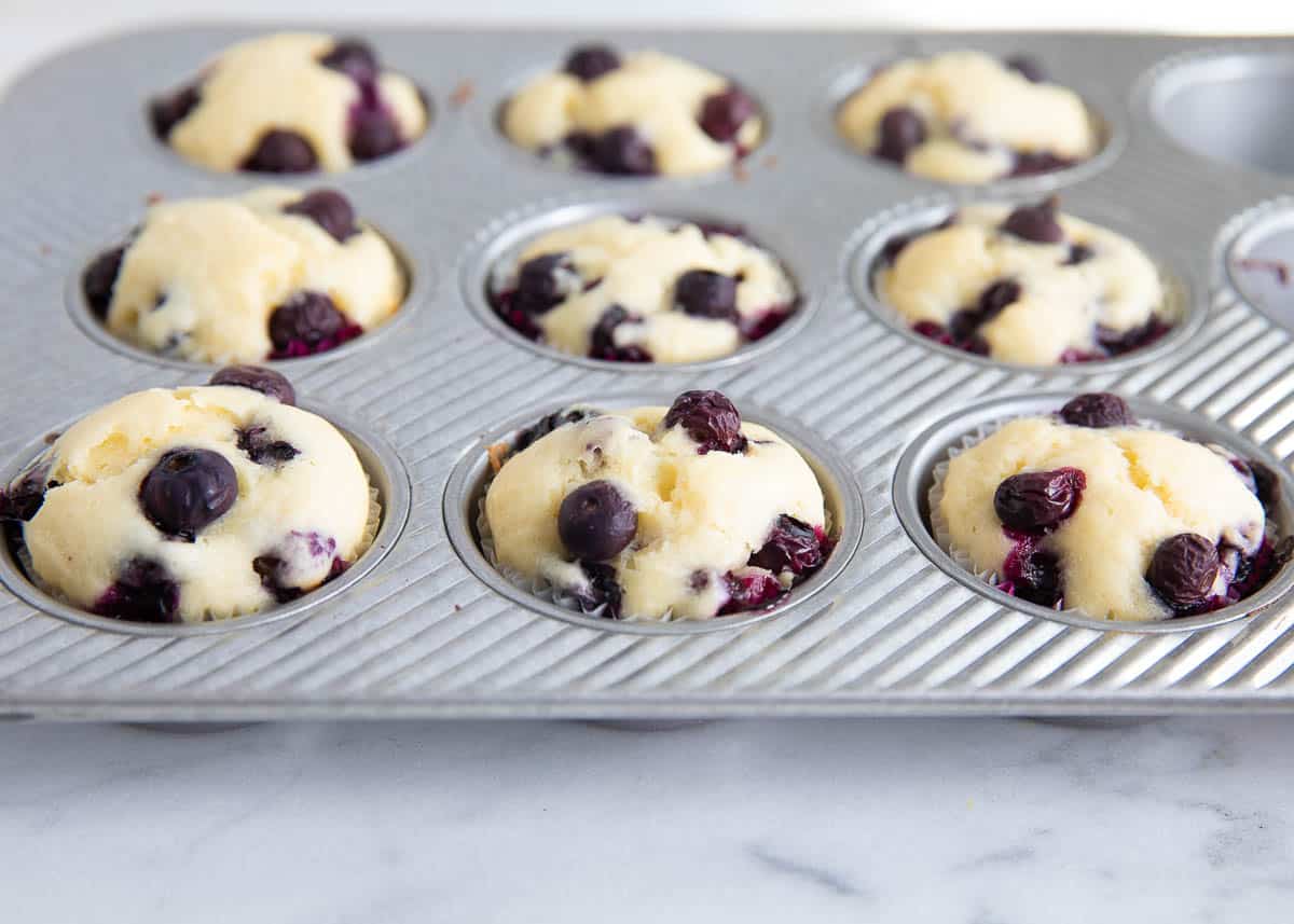 Freshly baked lemon blueberry muffins in muffin tin.