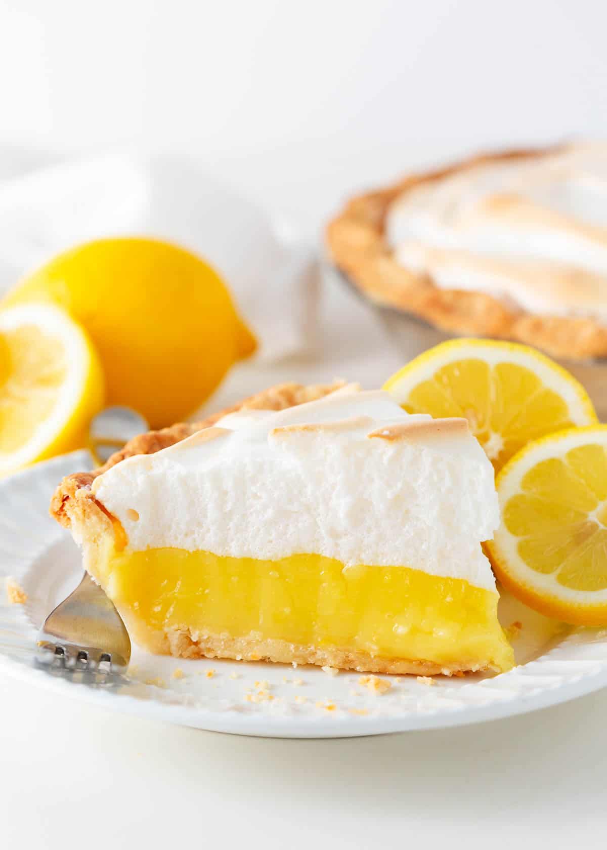 Slice of lemon meringue pie on a white plate.