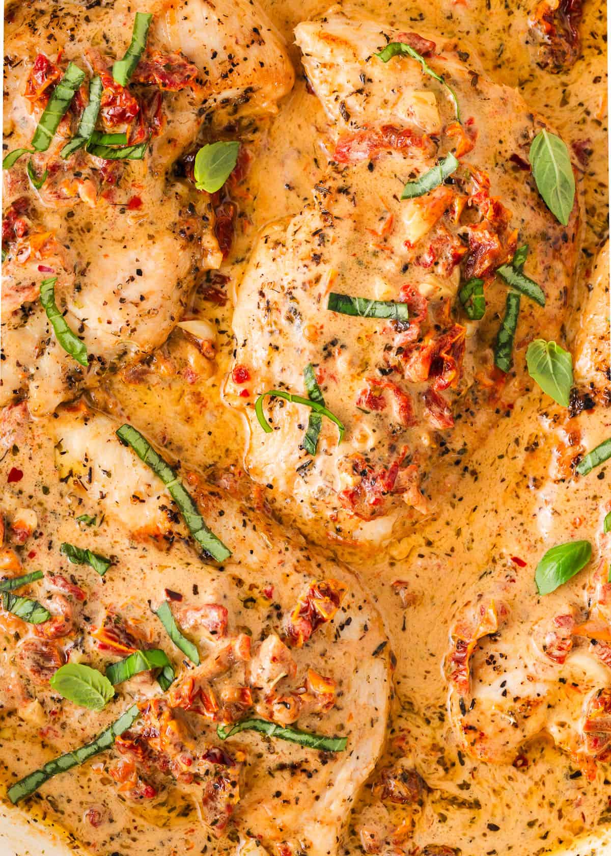 Close up of marry me chicken in a creamy sauce with sun dried tomatoes and basil. 