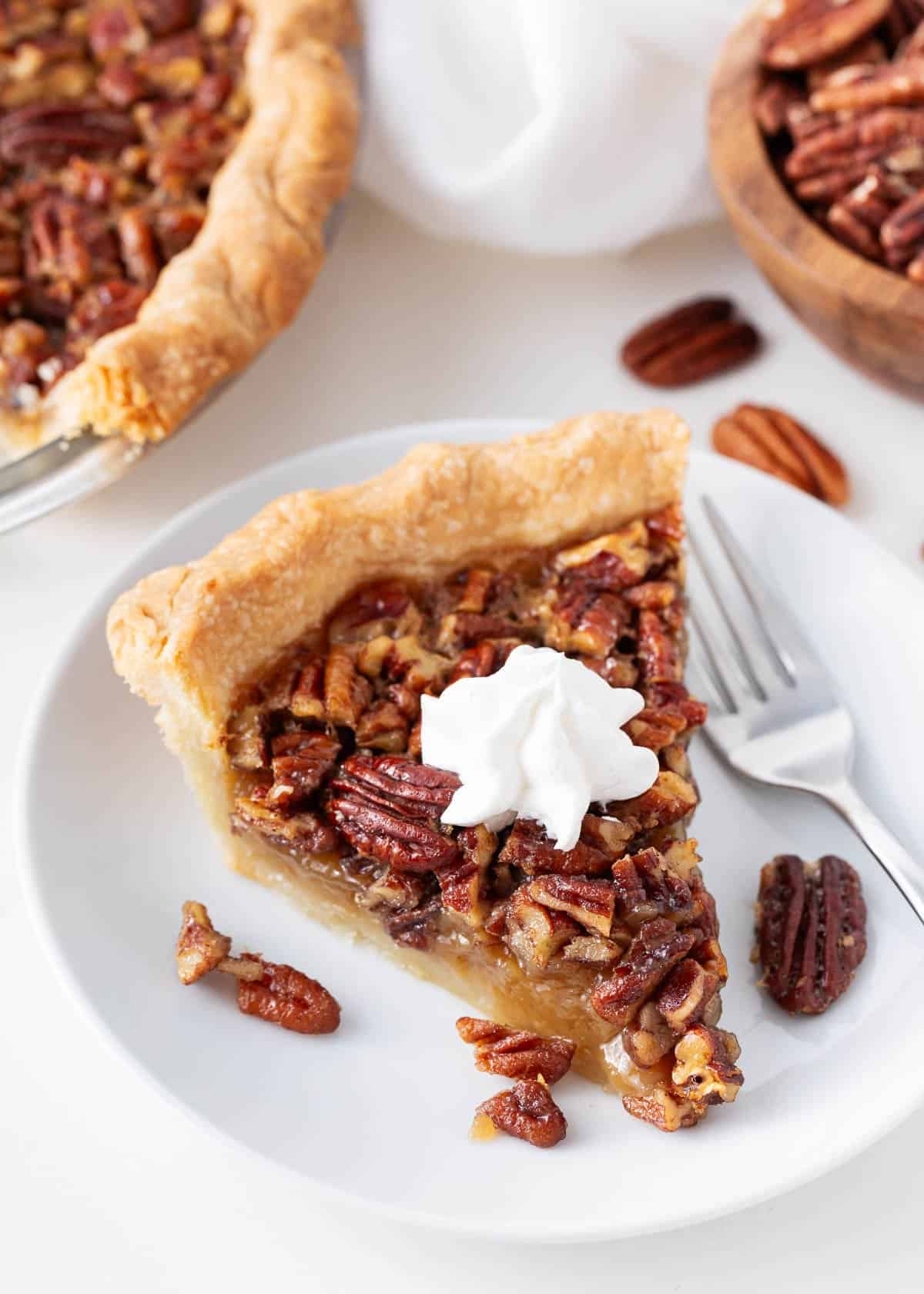 Slice of pecan pie on a white plate.