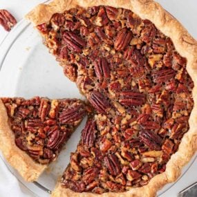 Slicing pecan pie in pie dish.