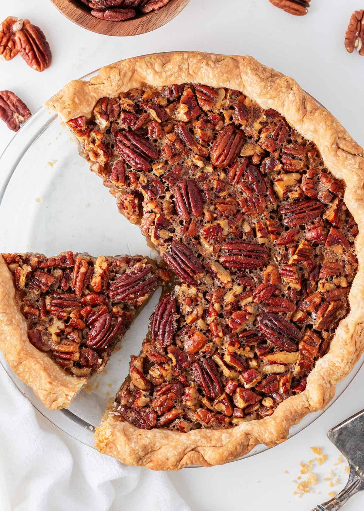 Slicing pecan pie in pie dish.