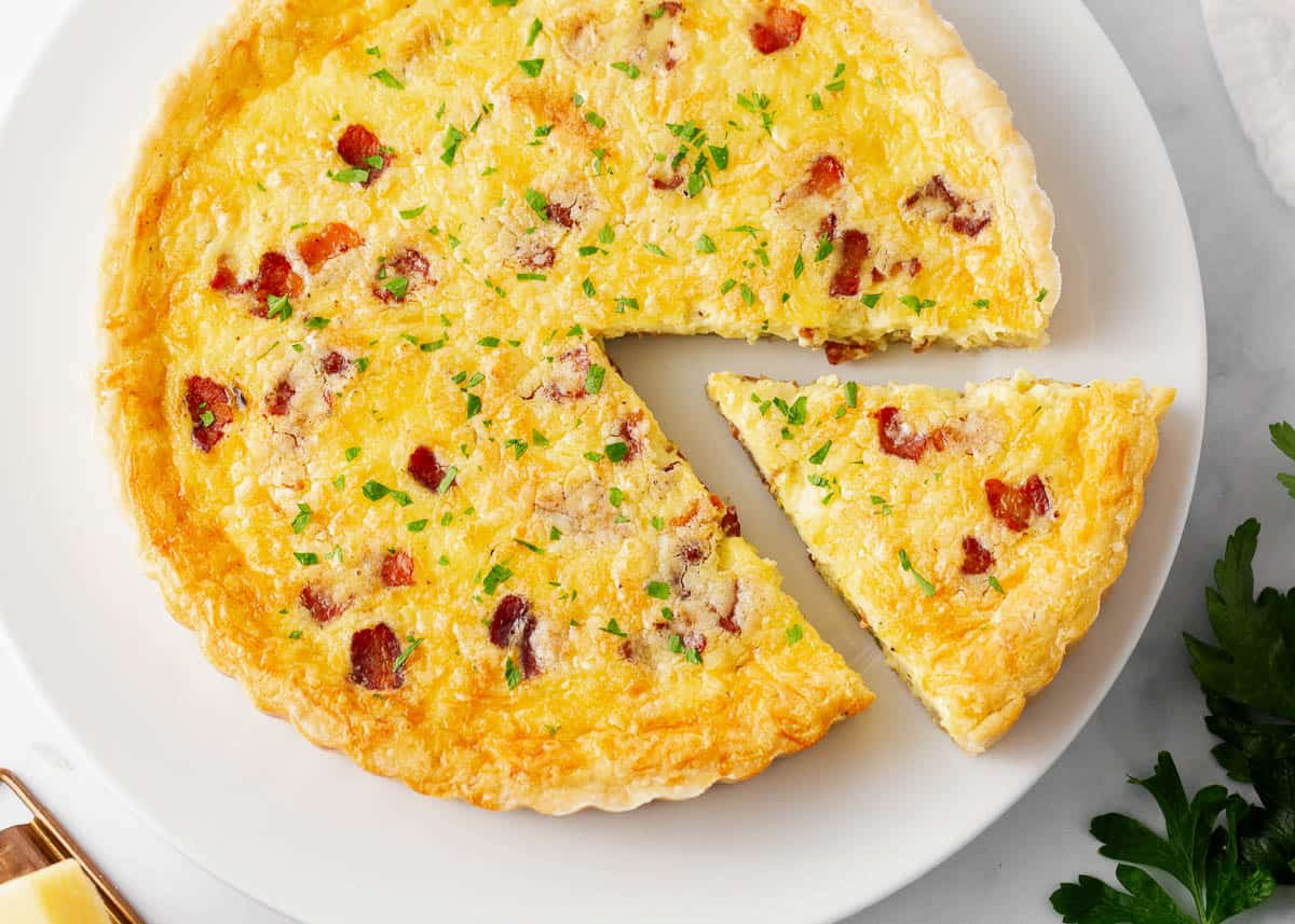 Slice of quiche lorraine on a white plate.