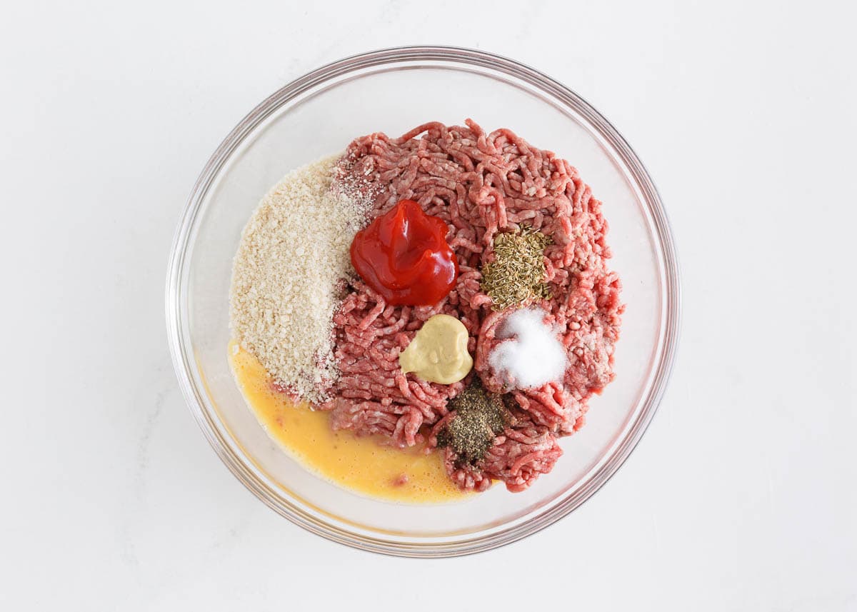 Ground beef with seasonings in a bowl.