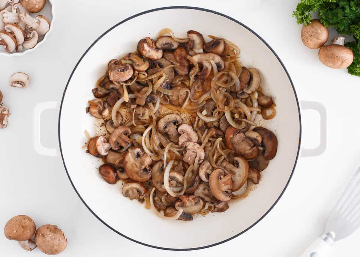 Mushrooms and onions in a white pot.
