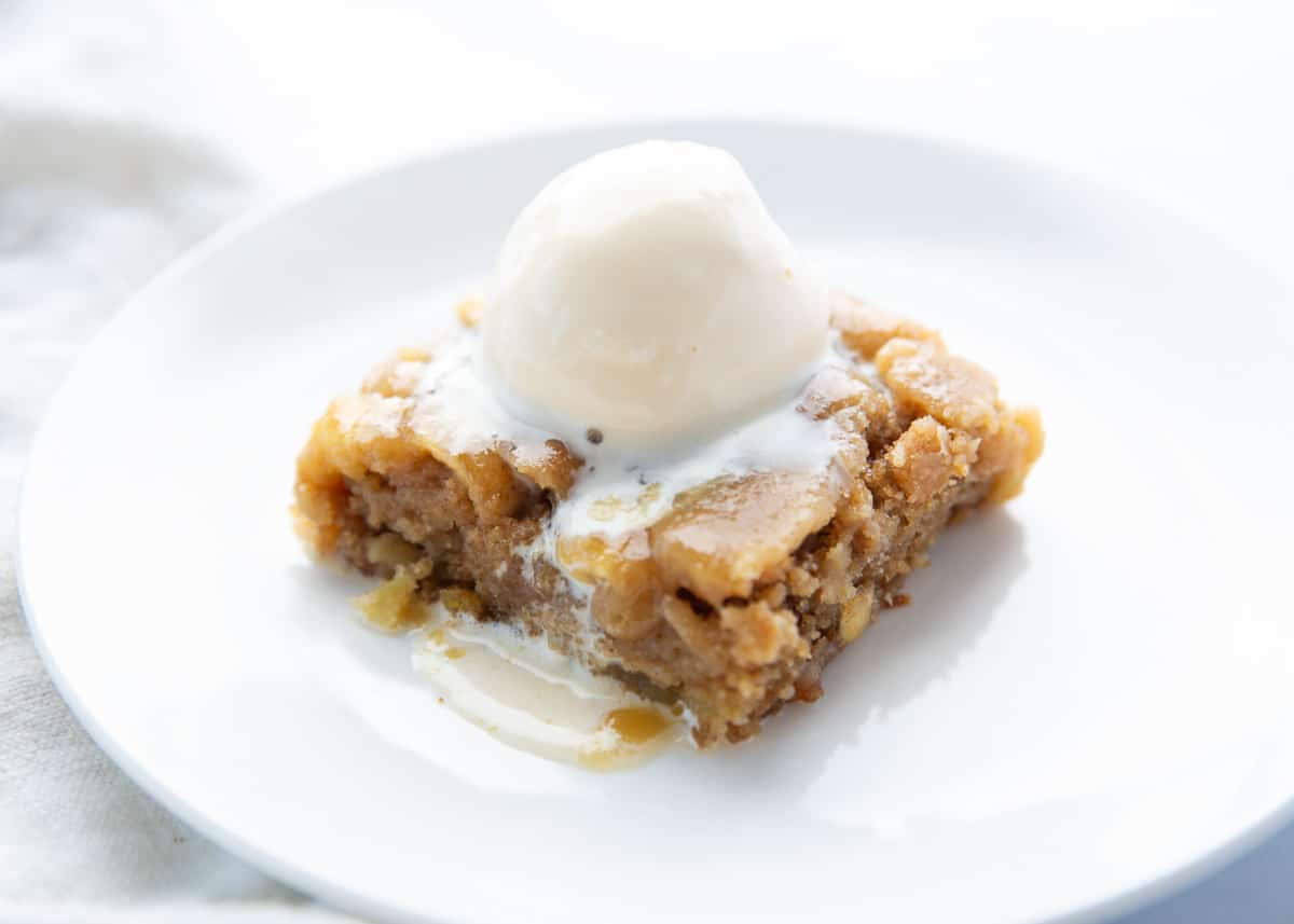 Apple cake with ice cream on a white plate.