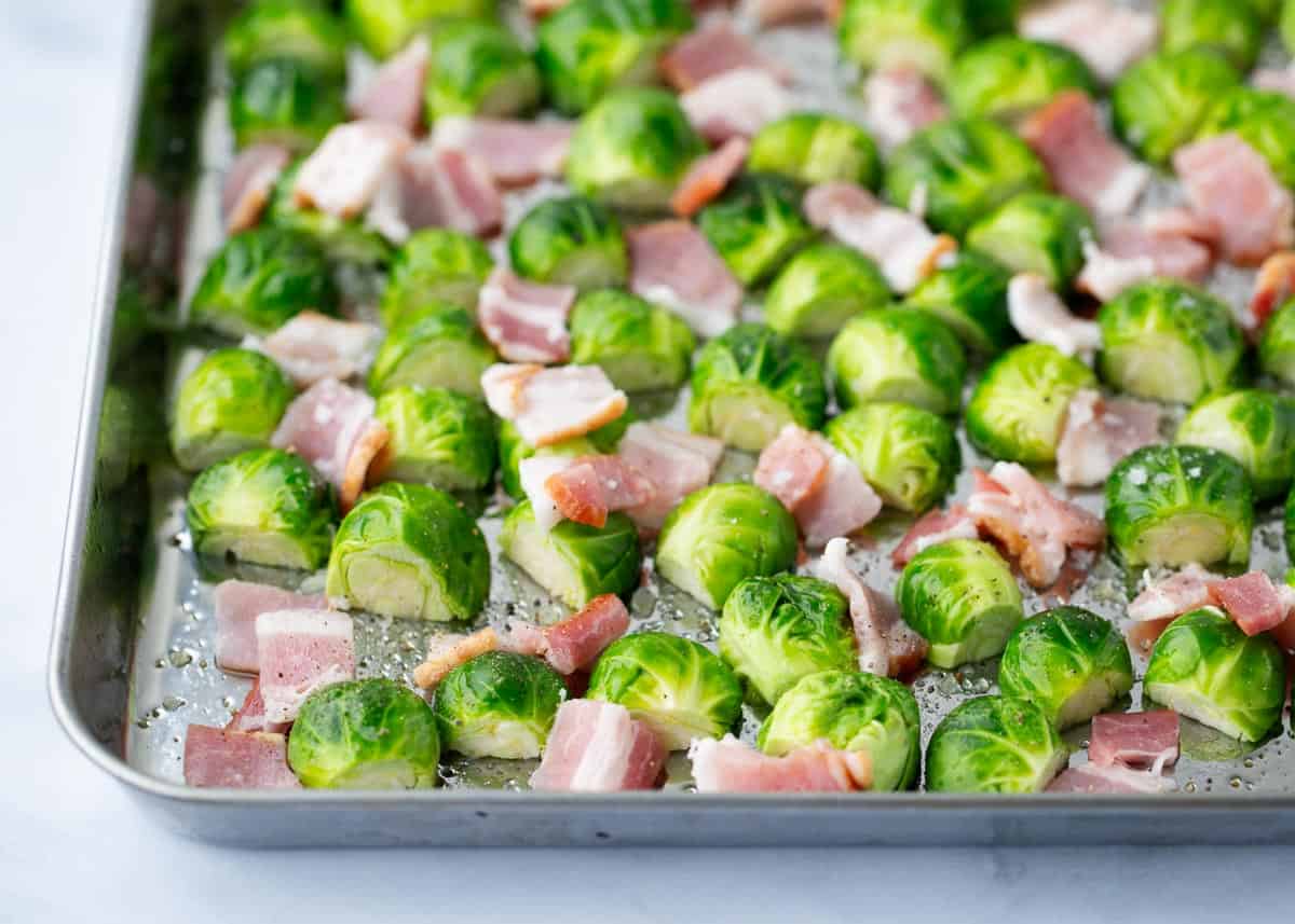 Cooking bacon and brussel sprouts on a pan.