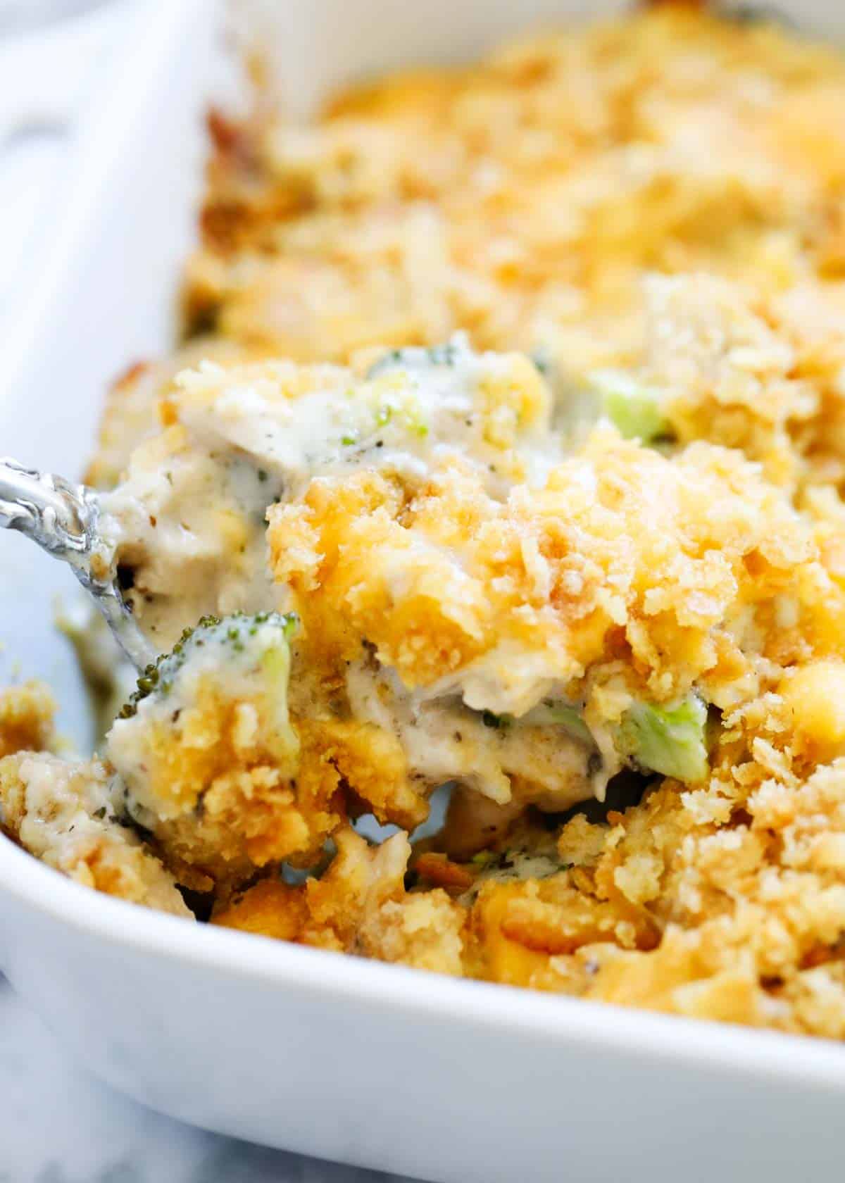 Chicken broccoli and rice casserole in with a spoon scooping out the casserole from the pan. 