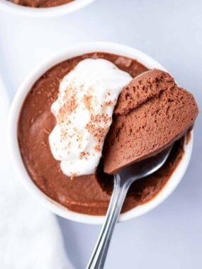 Easy chocolate mousse served in a white bowl, topped with whipped cream and a spoonful ready to enjoy.