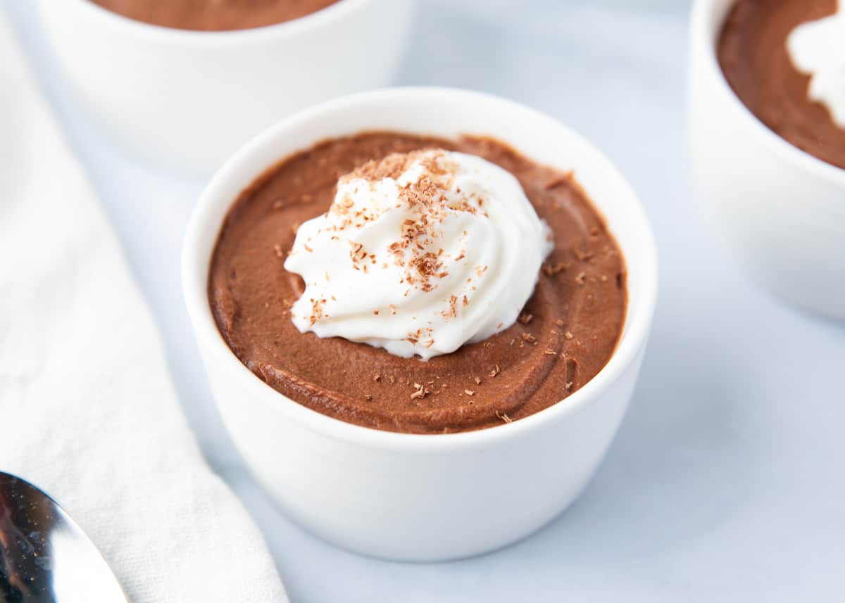 Chocolate mousse in a white bowl with whipped cream.