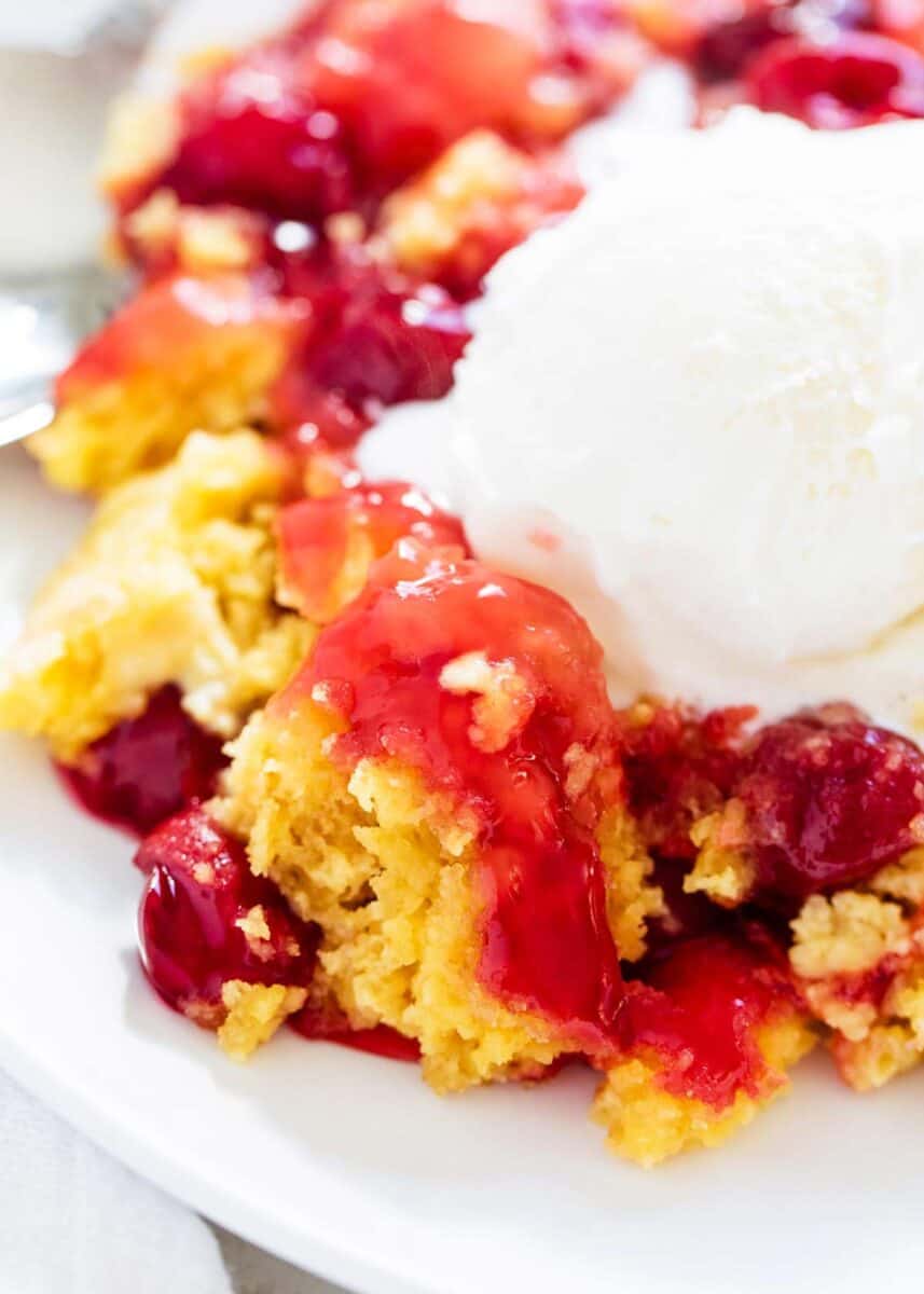 Cherry dump cake with a scoop of vanilla ice cream on top.