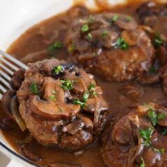 Juicy salisbury steak simmered in mushroom gravy, garnished with fresh parsley.