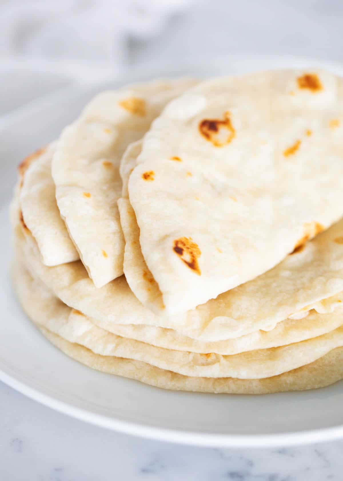 Up close photo of flour tortillas stacked on top of each other. 