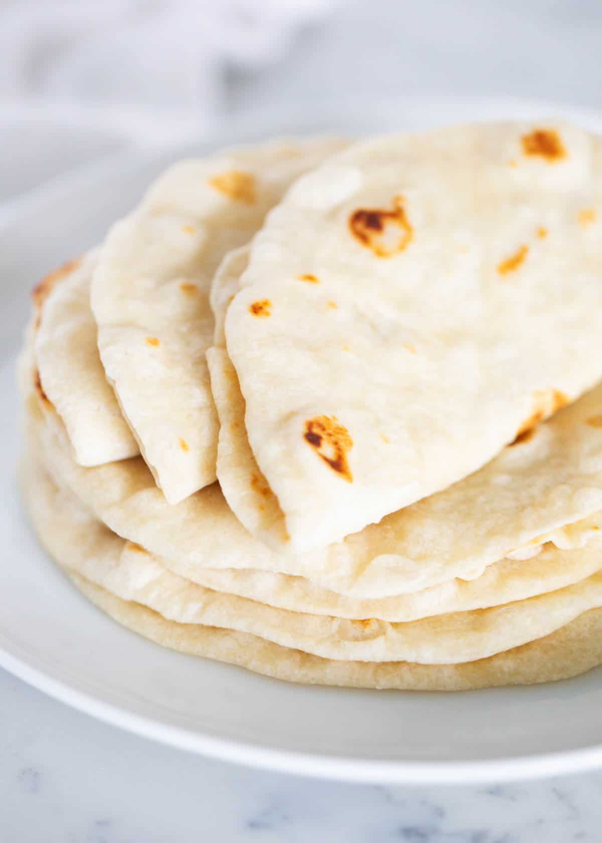 Up close photo of easy homemade flour tortilla recipe stacked on top of each other. 