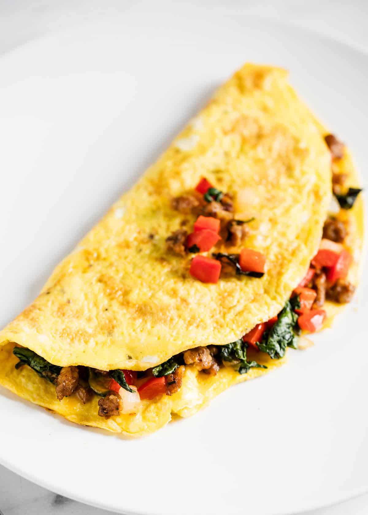 An omelette stuffed with ingredients on a white plate. 