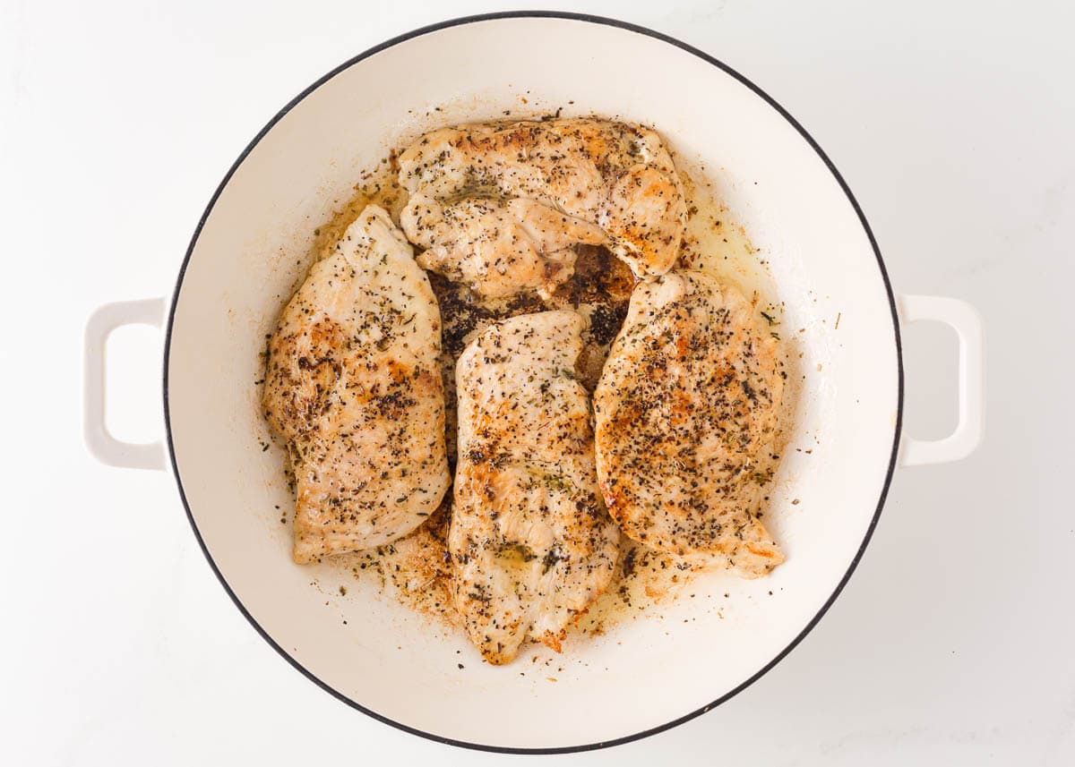 Seasoned chicken breasts in a skillet.