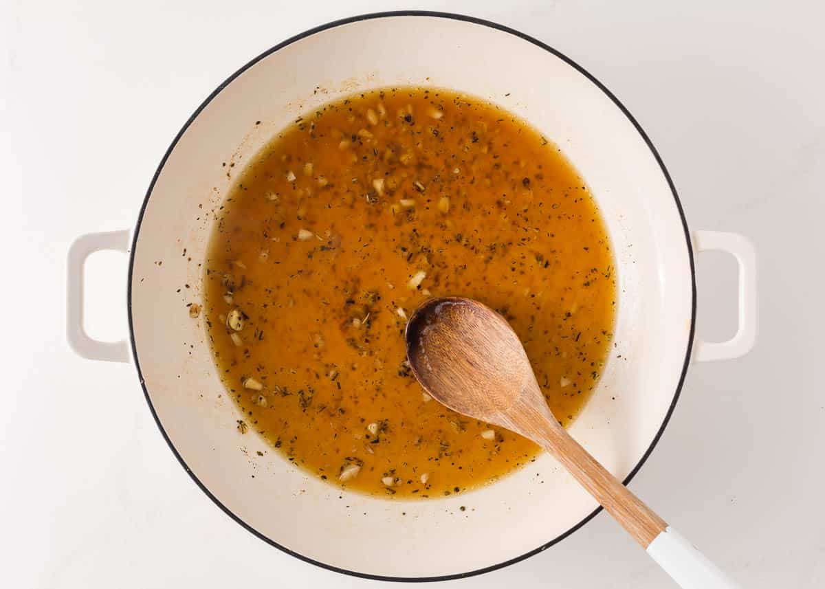 Sauteed garlic and broth in a pan.