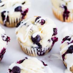 Lemon blueberry muffins with sour cream on the counter finished with a drizzle of glaze.