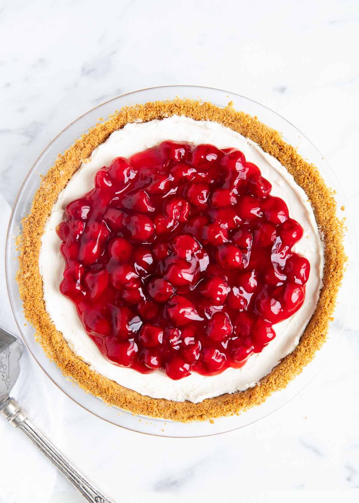 An overhead photo of no-bake cheesecake with cherry pie filling on top. 