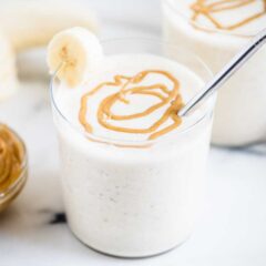 Easy peanut butter banana smoothie recipe served in clear glasses with a peanut butter drizzle on top.