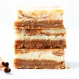 Stack of pumpkin cheesecake bars on a white counter.