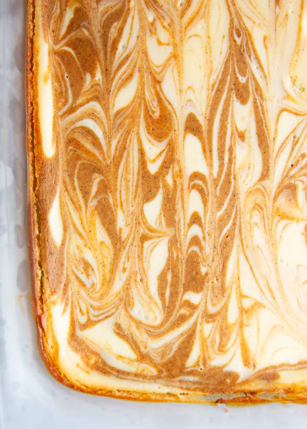 Pumpkin cheesecake bars in a glass dish.