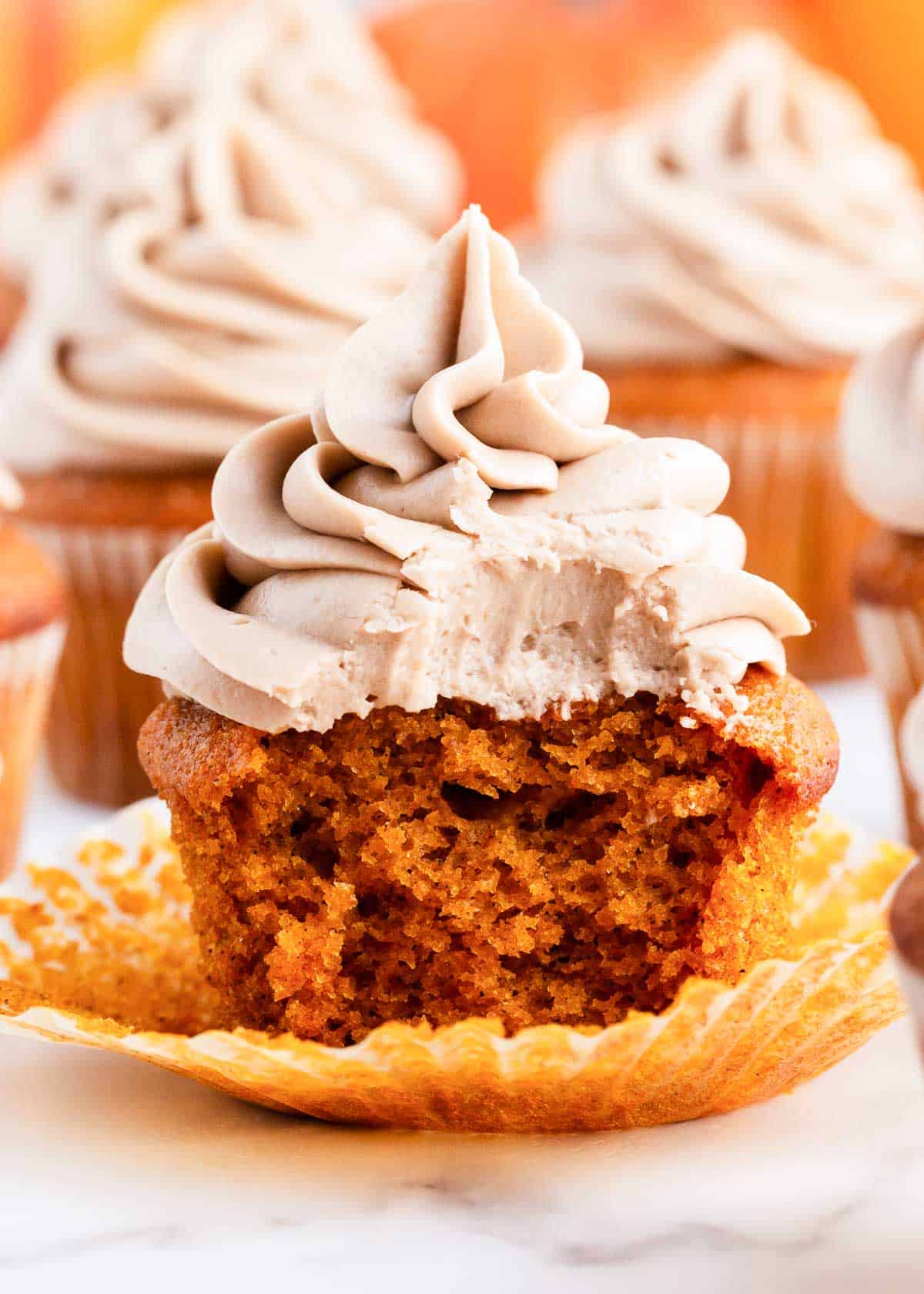 Pumpkin spice cupcake with a bite taken.