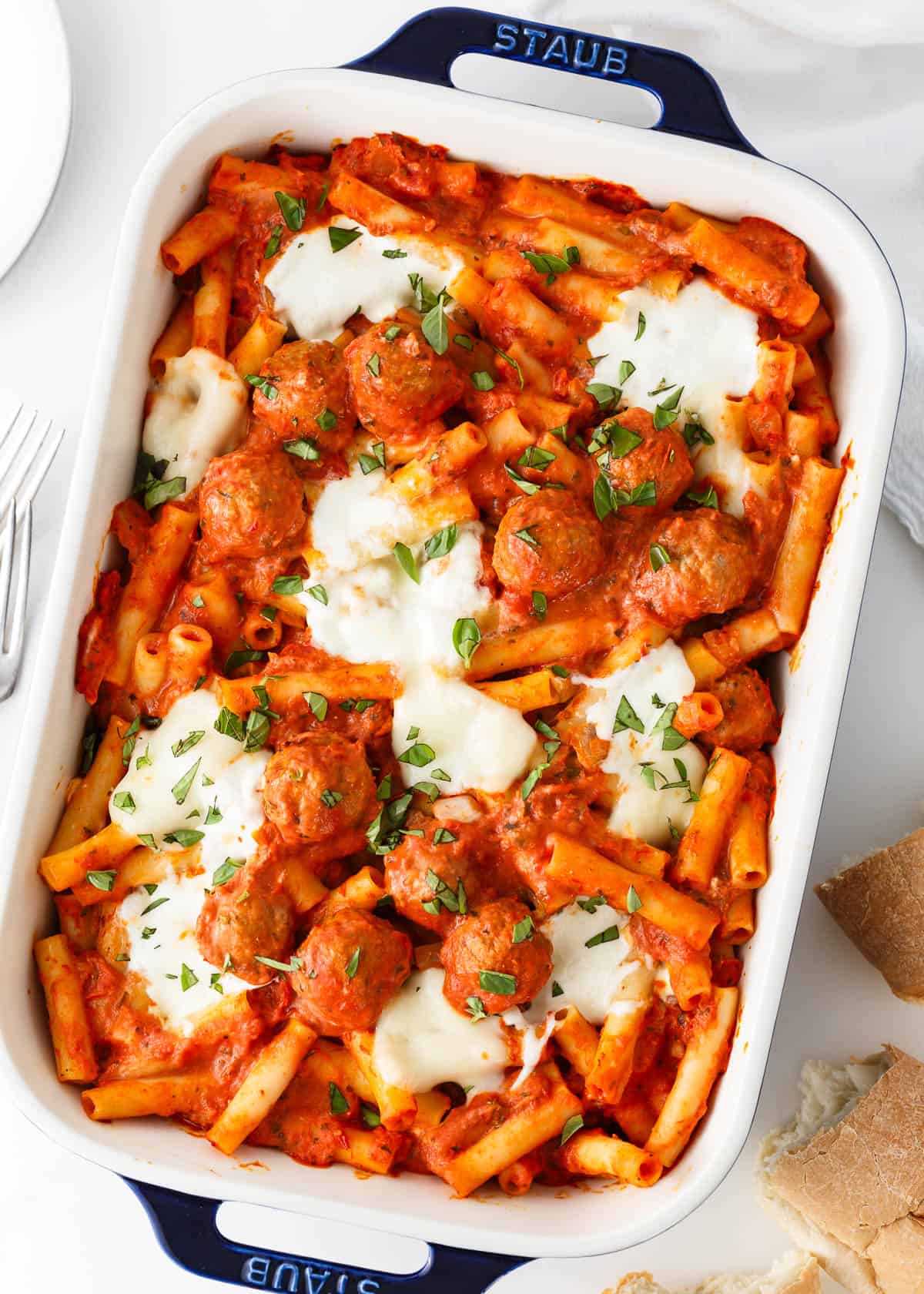 Baked ziti with meatballs baking in a baking dish.