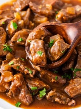 Crockpot beef tips and gravy being served from the slow cooker.
