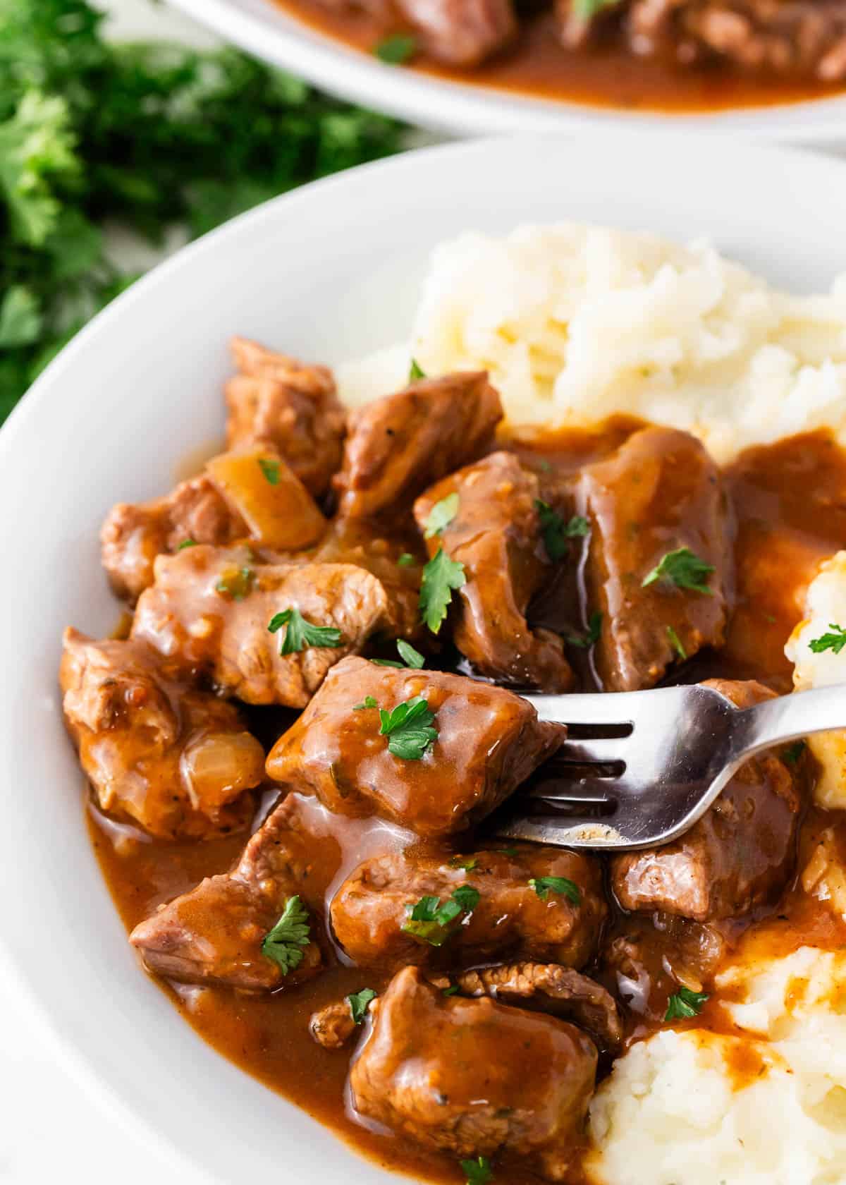 Beef tips and mashed potatoes in bowl.