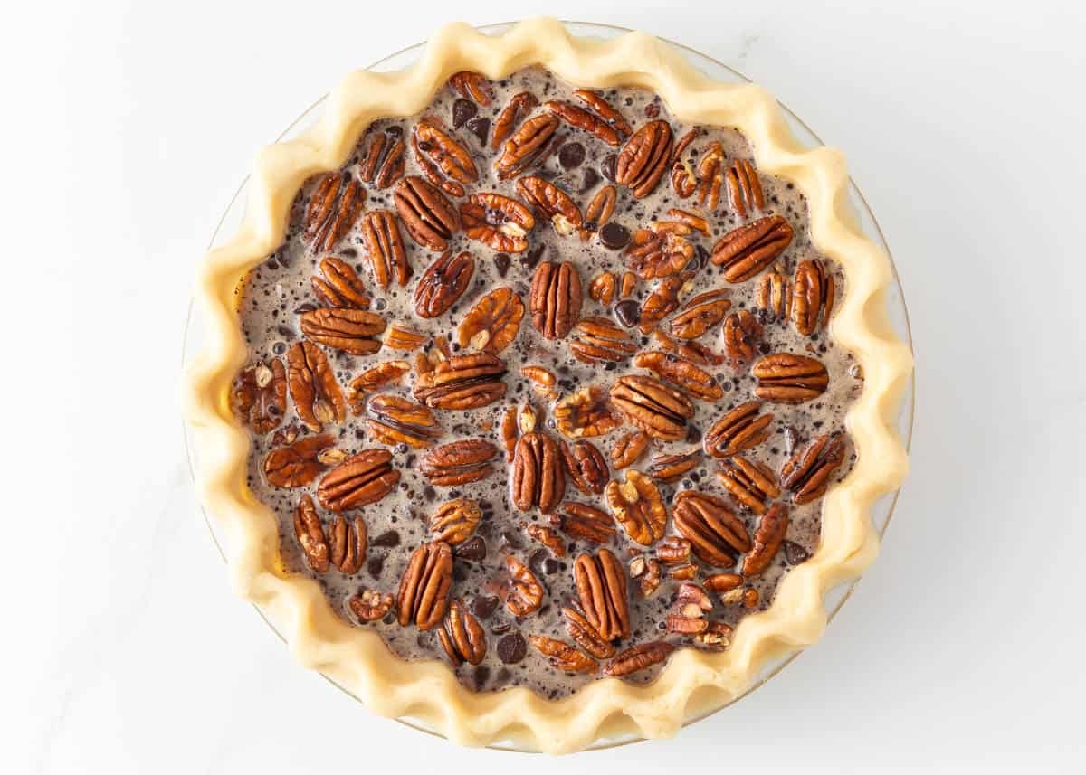 A luscious twist on a classic southern recipe, chocolate pecan pie is rich, velvety, and chocolatey loaded with pecans and topped with chocolate shavings and whipped cream. This is a decadent dessert you’ll want to show off! Showing how to make chocolate pecan pie.